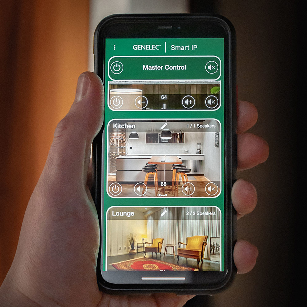 Ręka trzymająca smartfon z aplikacją Genelec Smart IP Controller do sterowania strefami audio