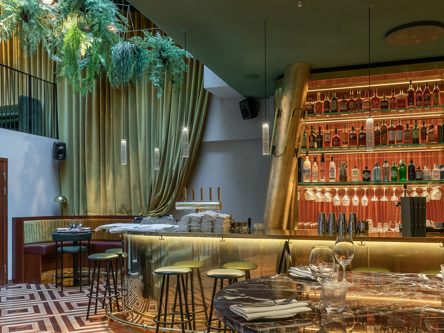 Wnętrze restauracji Brasserie Astoria w Sztokholmie: czarne głośniki Genelec Smart IP zamontowane na ścianach nad barem i strefą stolików